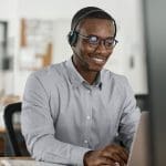 Smiling,African,Businessman,Talking,On,A,Headset,And,Using,A Dynamics 365 Sales